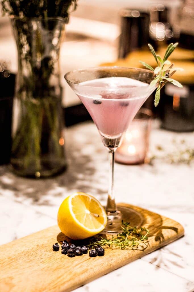 Queen Garnet Quencher in a cocktail glass, sitting on a wooden serving paddle